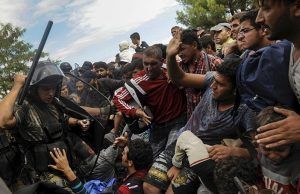 A Macedonian police officer raises his baton towards migrants to stop them from entering into Macedonia at Greece's border near the village of Idomeni, Greece, August 22, 2015. REUTERS/Alexandros Avramidis